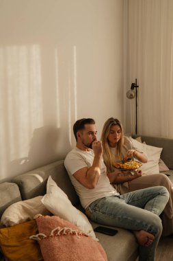 Bir çift sıcak lving odasında patates kızartması ve tavuk nugget paylaşıyor..