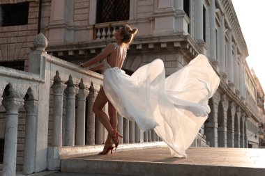 Venedik, İtalya 'daki tarihi taş köprünün üzerinde akıcı beyaz elbiseli zarif bir kadın..