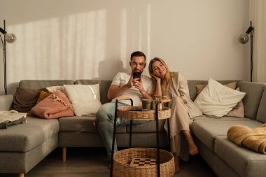 Smartphone kullanarak ve kahve içerek birlikte oturan mutlu çift..