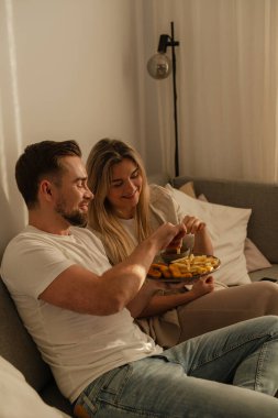 Bir çift sıcak lving odasında patates kızartması ve tavuk nugget paylaşıyor..