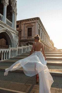 Venedik, İtalya 'daki tarihi taş köprünün üzerinde akıcı beyaz elbiseli zarif bir kadın..