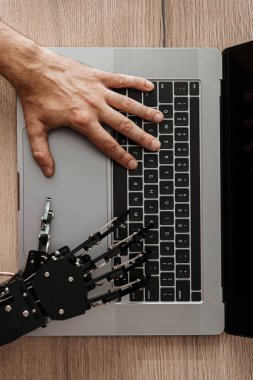 İnsan eli ve robotik el bilgisayarda birlikte yazma, yapay zeka işbirliği, insan-makine etkileşimi, ve gelecekteki teknoloji.