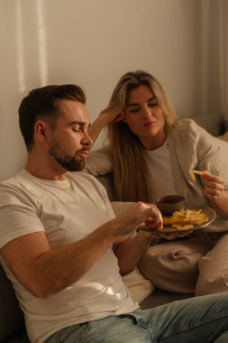 Bir çift sıcak lving odasında patates kızartması ve tavuk nugget paylaşıyor..