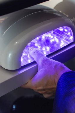 Jel manikür tedavisinde müşterinin elleri mor ötesi lambanın altında..