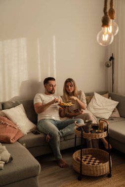 Bir çift sıcak lving odasında patates kızartması ve tavuk nugget paylaşıyor..