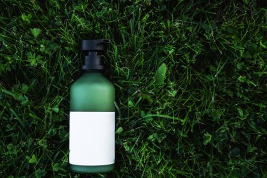 Çevre dostu yeşil, üzerinde beyaz bir etiket bulunan çimenlerin üzerinde yeniden kullanılabilir bir şişe..