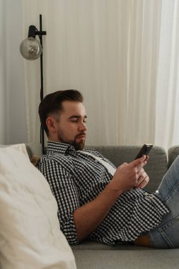 Rahat Adam Evdeki Kanepede uzanırken Akıllı Telefona Bakıyor.