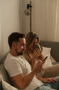 Smartphone kullanarak ve kahve içerek birlikte oturan mutlu çift..