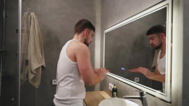 Yıkandıktan sonra Yüze Nemlendirici Uygulayan Adam.