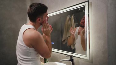 Yıkandıktan sonra Yüze Nemlendirici Uygulayan Adam.