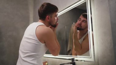 Yıkandıktan sonra Yüze Nemlendirici Uygulayan Adam.