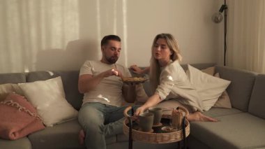 Bir çift sıcak oturma odasında patates kızartması ve tavuk nugget paylaşıyor..