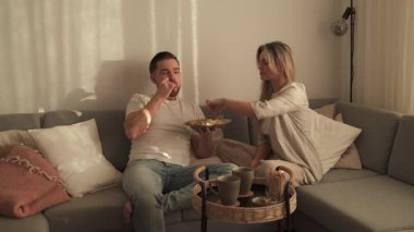 Bir çift sıcak oturma odasında patates kızartması ve tavuk nugget paylaşıyor..