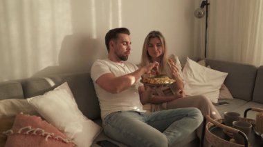 Bir çift sıcak oturma odasında patates kızartması ve tavuk nugget paylaşıyor..