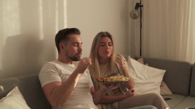 Bir çift sıcak oturma odasında patates kızartması ve tavuk nugget paylaşıyor..