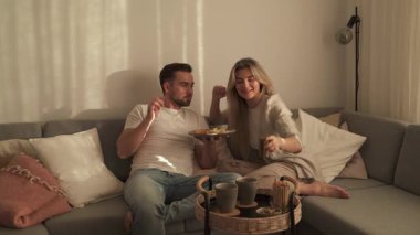 Bir çift sıcak oturma odasında patates kızartması ve tavuk nugget paylaşıyor..