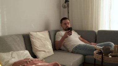 Rahat Adam Evdeki Kanepede uzanırken Akıllı Telefona Bakıyor.