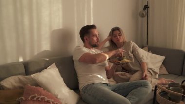 Bir çift sıcak oturma odasında patates kızartması ve tavuk nugget paylaşıyor..