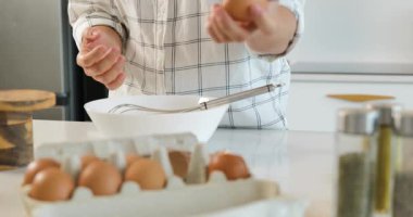 Eller taze yumurta kırıyor ve mutfak tezgahındaki bir kasede omlet çırpıyor..