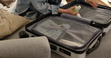 Seyahatten sonra evde sert bir bavuldan giysileri çıkaran bir kadın..