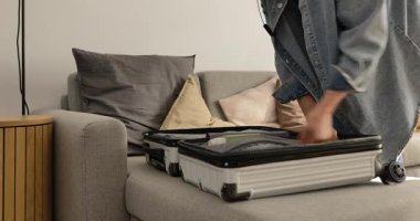 Seyahatten sonra evde sert bir bavuldan giysileri çıkaran bir kadın..