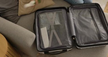 Seyahatten sonra evde sert bir bavuldan giysileri çıkaran bir kadın..