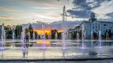 Şehir meydanında gün batımında çeşme var.