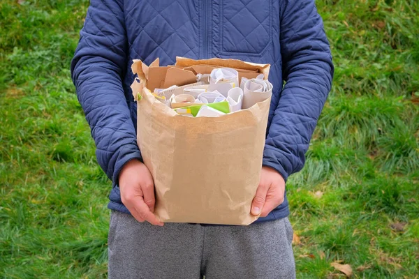 Paper and cardboard prepared for recycling. Bundles of cardboard to be recycled. Man holds a package of paper and cardboard in his hand for recycling.