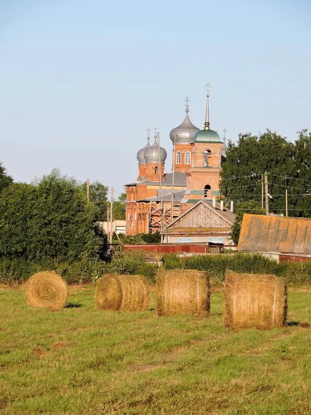石の教会 ロシアの田舎のフィールド上の干し草の山の俵 — ストック写真
