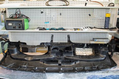 Ters dönmüş bir araba konsolu bir oto tamirhanesindeki bir elektrikçinin tezgahında duruyor.