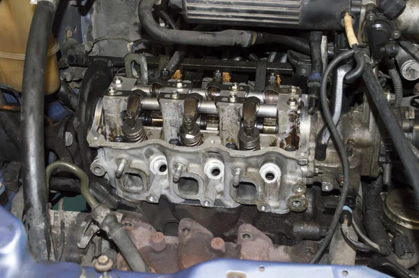 The block head of a three cylinder petrol automobile internal combustion engine without a valve cover installed under the hood of the car