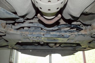 Bottom rear view of the front subframe of the car which is hanging on the lift in the car repair shop clipart