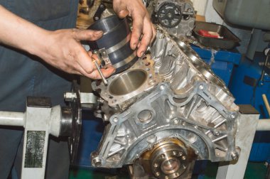 Tamirci, mandrel 'i motor silindir bloğuna pistonu yerleştirmek için hazırlar. Bu da oto tamir atölyesindeki motor tamir standına monte edilir.