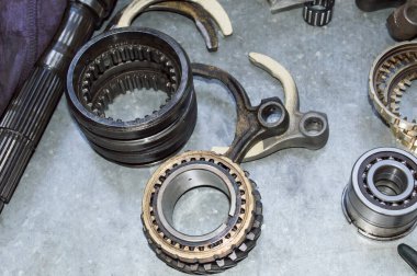 Vites kolu çatalları ve arabanın manuel vites senkronizatörünün elementleri oto tamirhanesinde çalışan bir metalin üzerinde duruyor.