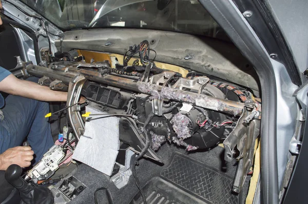 The electrician performs work in the car interior with the instrument panel removed