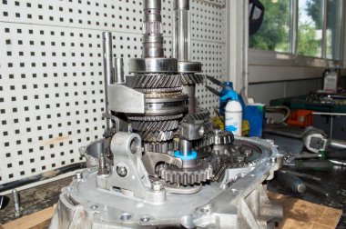 Birincil ve ikincil şaftların ve otomobil tamirhanesindeki çalışma masasında duran kısmen sökülmüş bir otomobil manuel şanzımanının ana teçhizatının görüntüsü