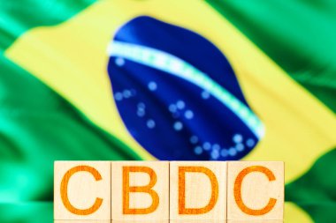 CBC Brezilya 'dan. Brezilya bayrağının arka planında CBDC yazılı tahtadan küpler.