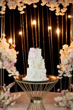 Düğün pastası narin bir tarzda geceleyin kemerin arka planına karşı