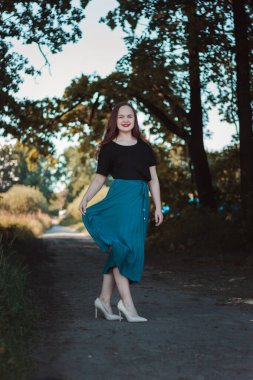 Büyümüş güzel, zarif bir kız. Parkta yürü. Turkuaz etekli ve bej topuklu mutlu şirin kız..