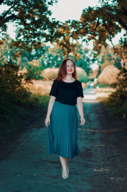 Büyümüş güzel, zarif bir kız. Parkta yürü. Turkuaz etekli ve bej topuklu mutlu şirin kız..