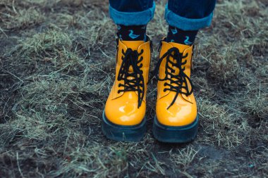 Çimenlerin arka planına karşı sarı sert ayakkabılar. Kadın ayağı işte. Çok güzel bir arka plan. Metin için bir yer.