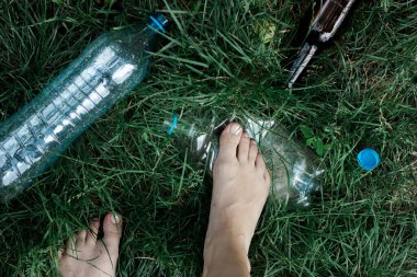 Ekoloji konsepti. İnsan ayağı yeşil çimlerde plastik bir şişeyi ezer.. 