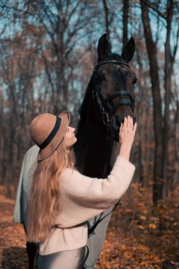 Kadınlar, sonbahar mevsiminde at başında dikilirken şapka ve kazak giyerler.