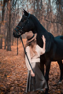 Kadınlar, sonbahar mevsiminde at başında dikilirken şapka ve kazak giyerler.