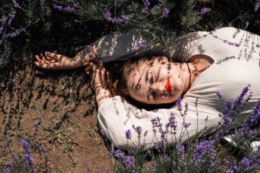 Açık bir günde kadın lavanta tarlasında güneşlenir.