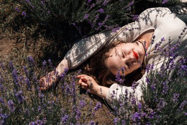 Açık bir günde kadın lavanta tarlasında güneşlenir.