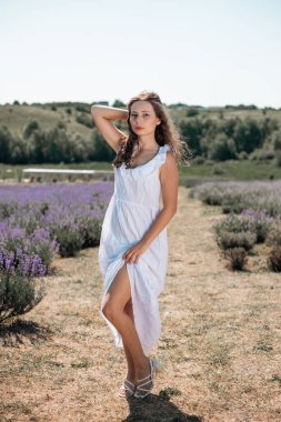 Genç bir kadın güneşli bir günde lavanta tarlasında yürüyor.