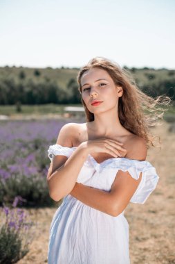 Genç bir kadın güneşli bir günde lavanta tarlasında yürüyor.