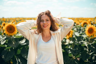 Kolları havada gülümseyen kadın yaz öğleden sonra güneşli bir günün tadını çıkarıyor.