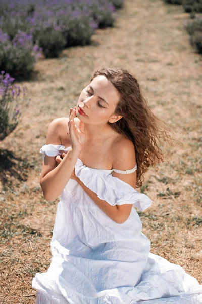 Gündüz vakti lavanta çiçeklerinin arasında diz çöküp doğa ve açık havada eğlenen bir kadın.